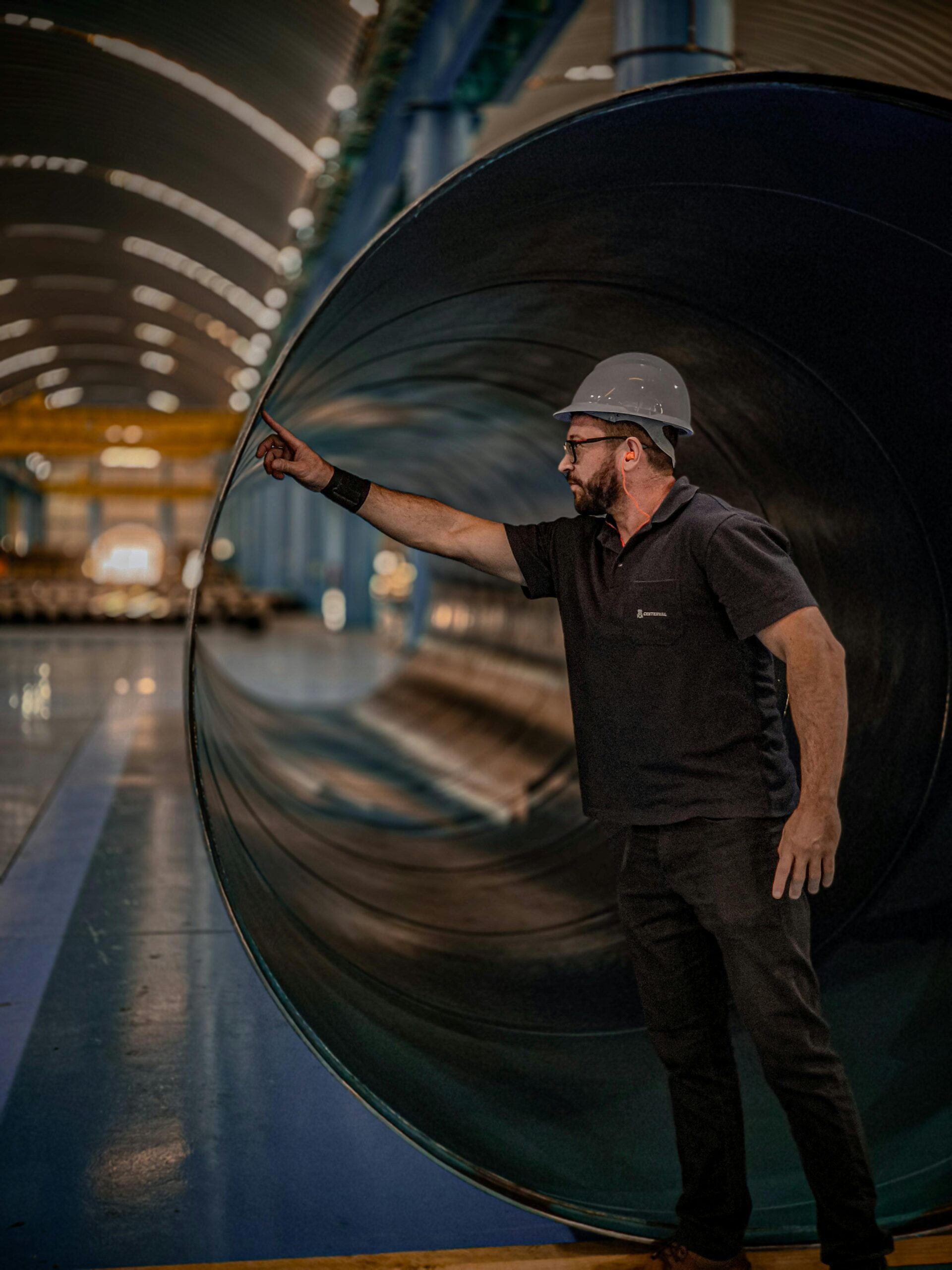 Industrial worker inspecting a large rolled steel pipe