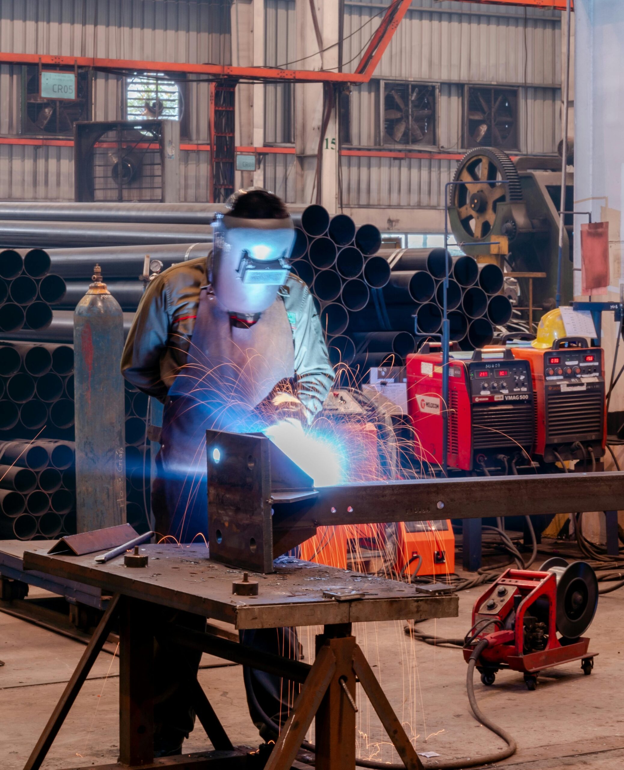 Active welding with bright blue arc and sparks in a workshop with steel pipes