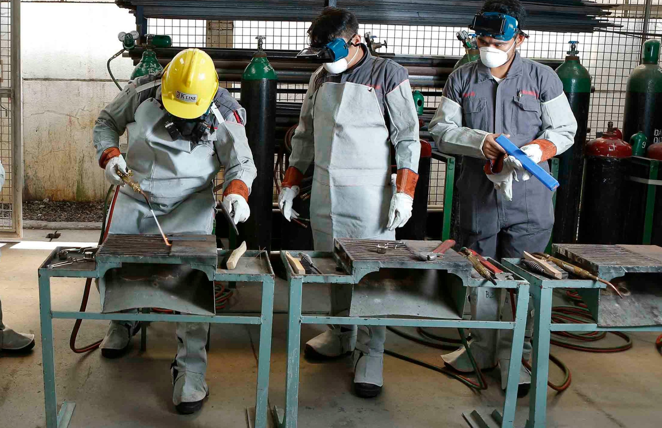 Workers in full PPE training on welding exercises at benches